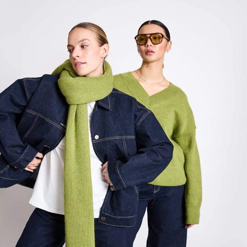 Zwei Frauen in herbstlicher Mode mit dunkelblauer Jeansjacke, grünem Strickpullover und Schal.