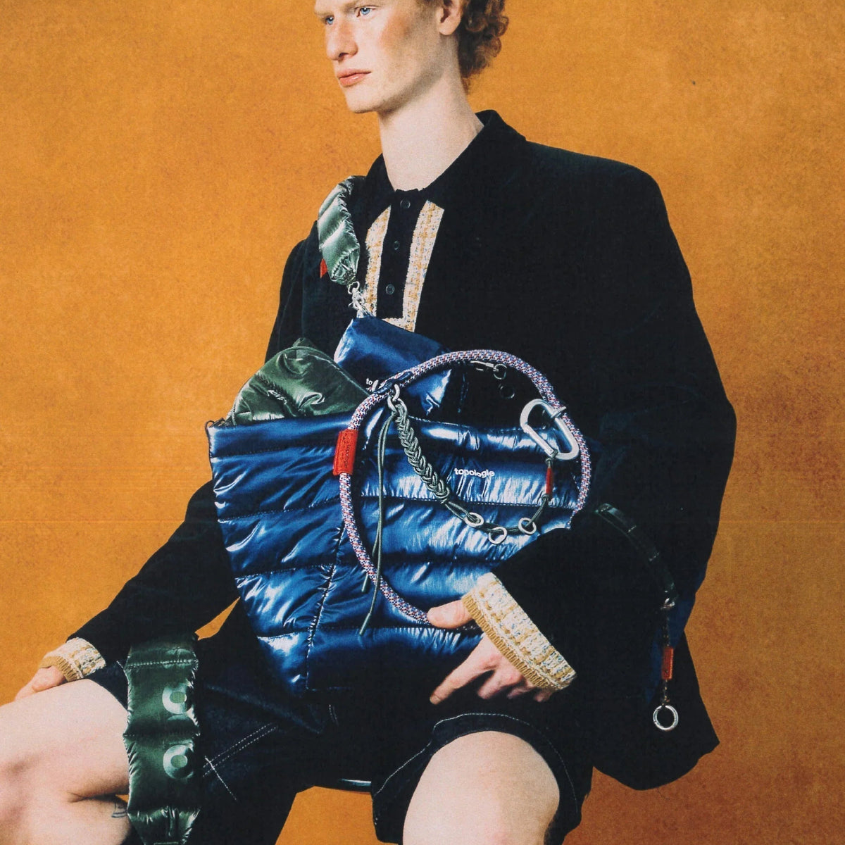 Mann mit schwarzem Hemd und einer blauen, gesteppten Tasche mit Kletterseil-Details.