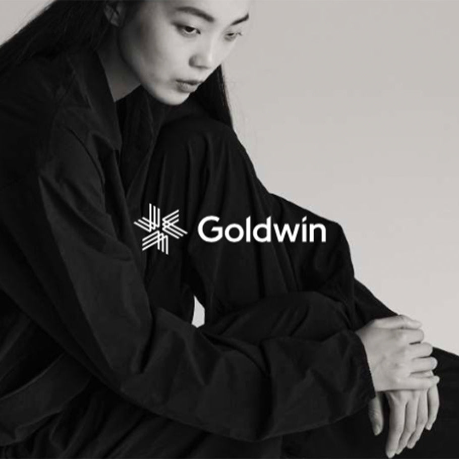 Frau in schwarzer Goldwin Jacke und Hose in minimalistischem Schwarz-Weiß-Portrait.