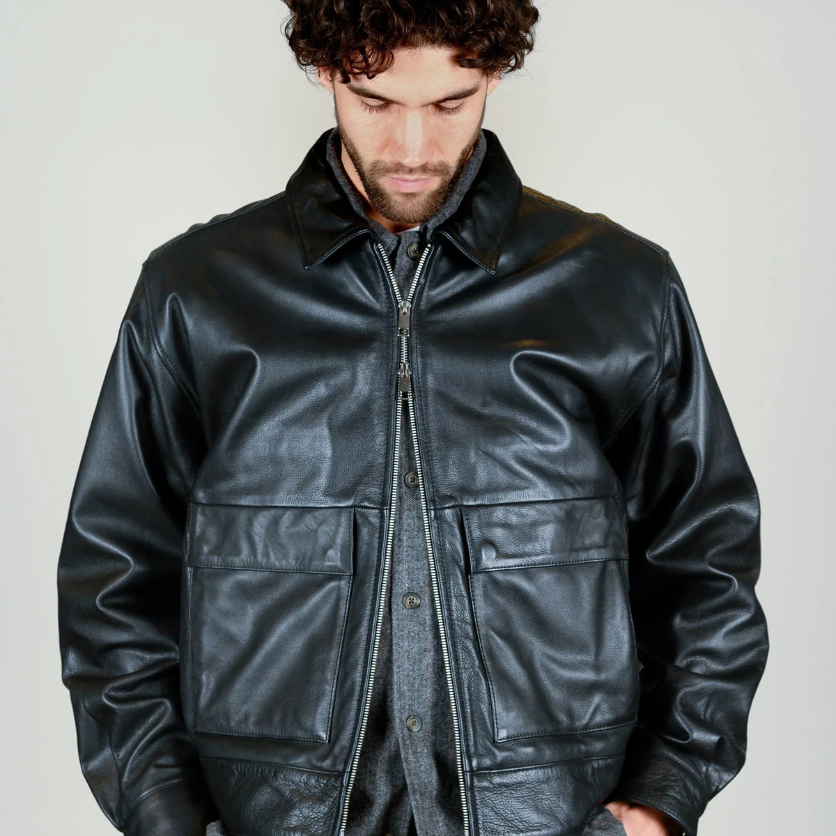 Mann in schwarzer Lederjacke und grauer Stoffhose aus dem Herbst/Winter Lookbook.