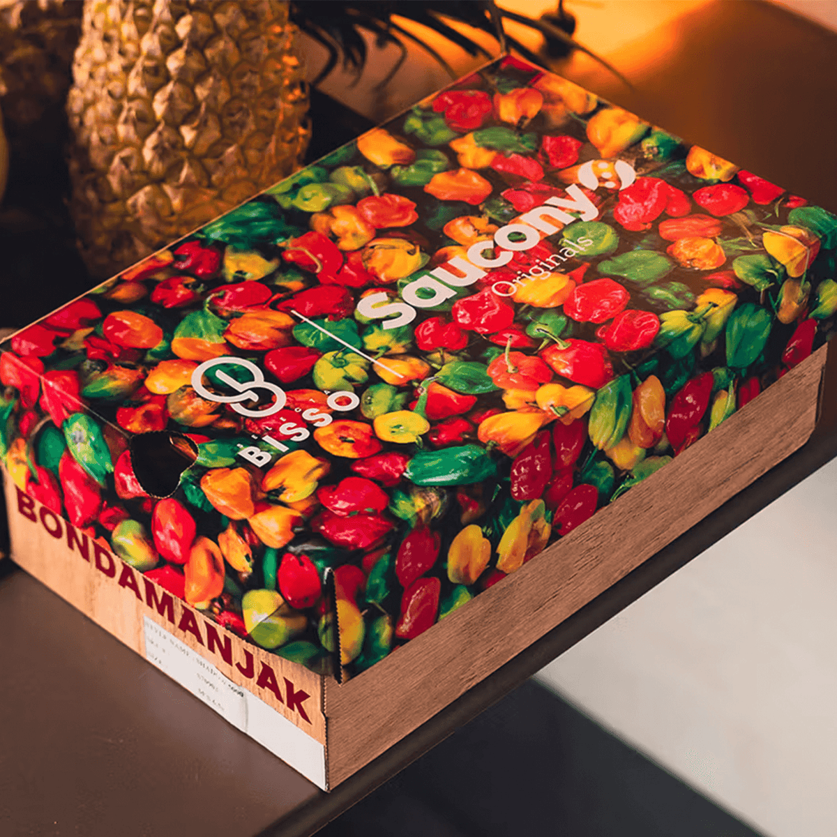 Saucony Shadow 5000 x BISSO Schuhkarton mit buntem Chili-Print auf Holzkiste