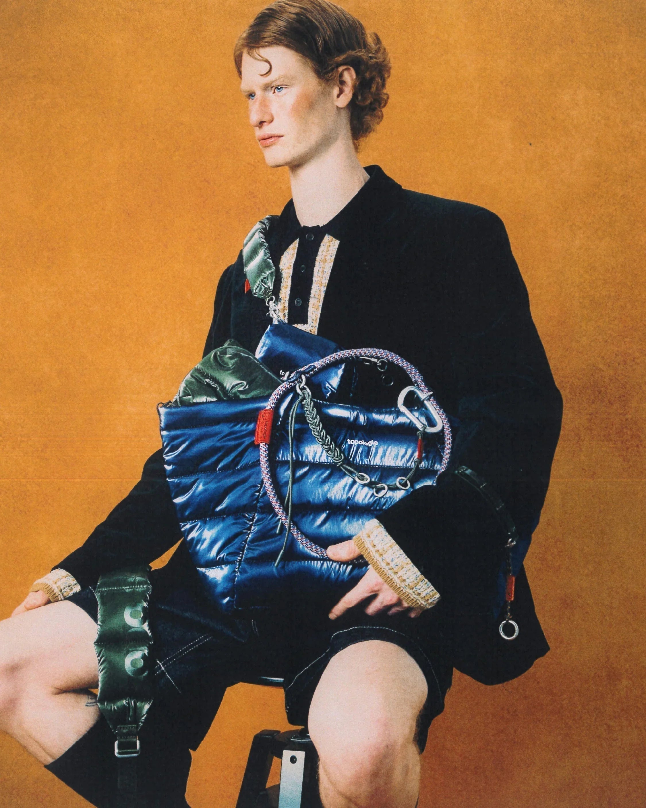 Mann mit schwarzem Hemd und einer blauen, gesteppten Tasche mit Kletterseil-Details.