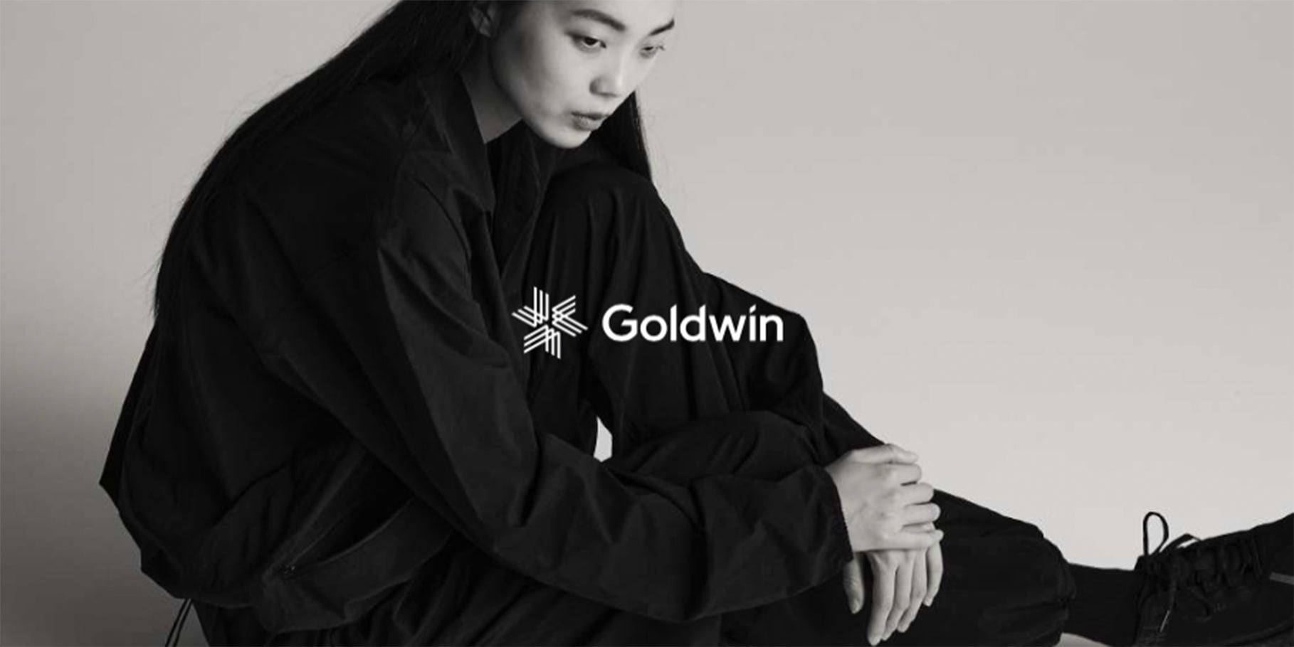 Frau in schwarzer Goldwin Jacke und Hose in minimalistischem Schwarz-Weiß-Portrait.