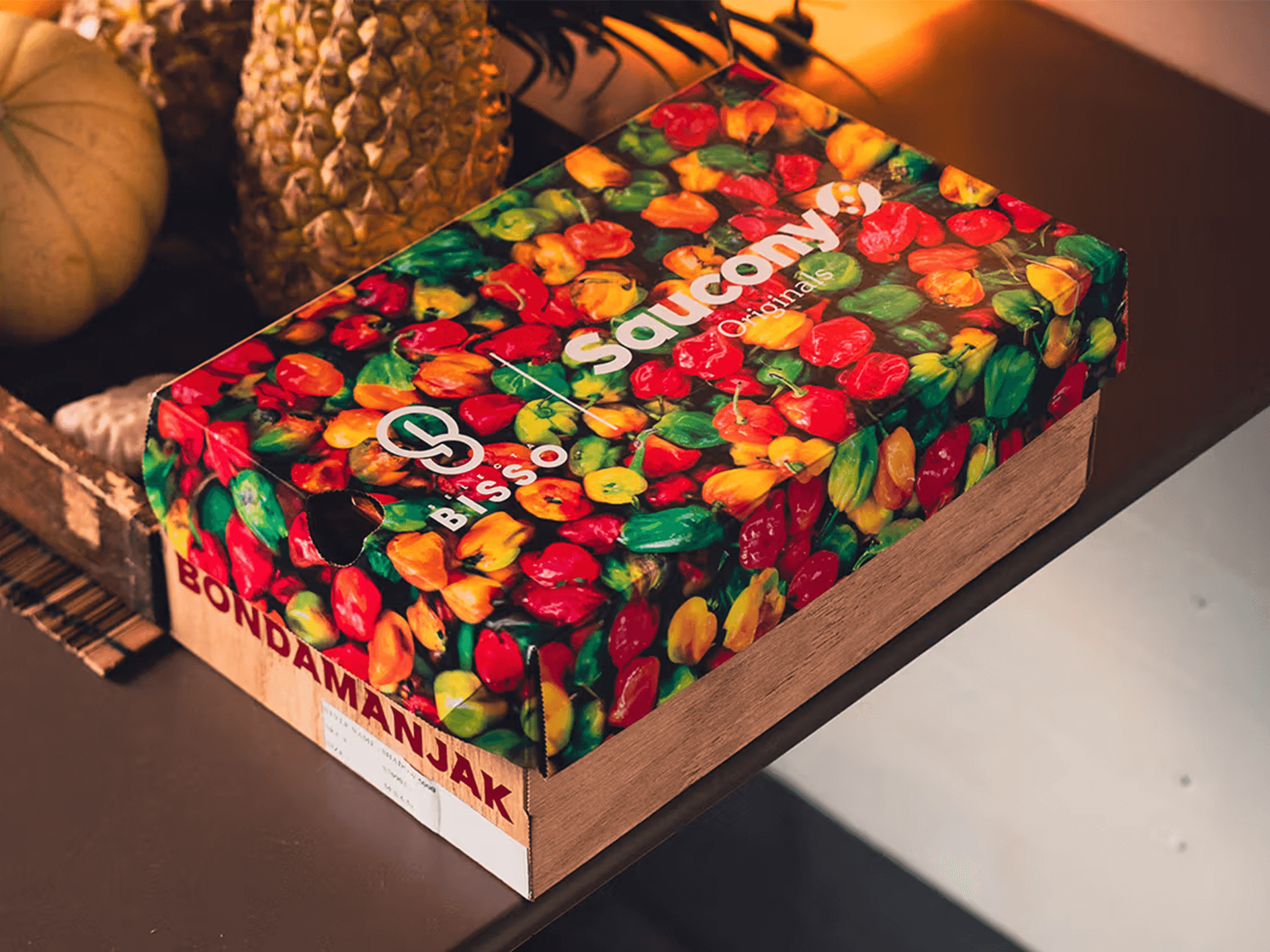 Saucony Shadow 5000 x BISSO Schuhkarton mit buntem Chili-Print auf Holzkiste