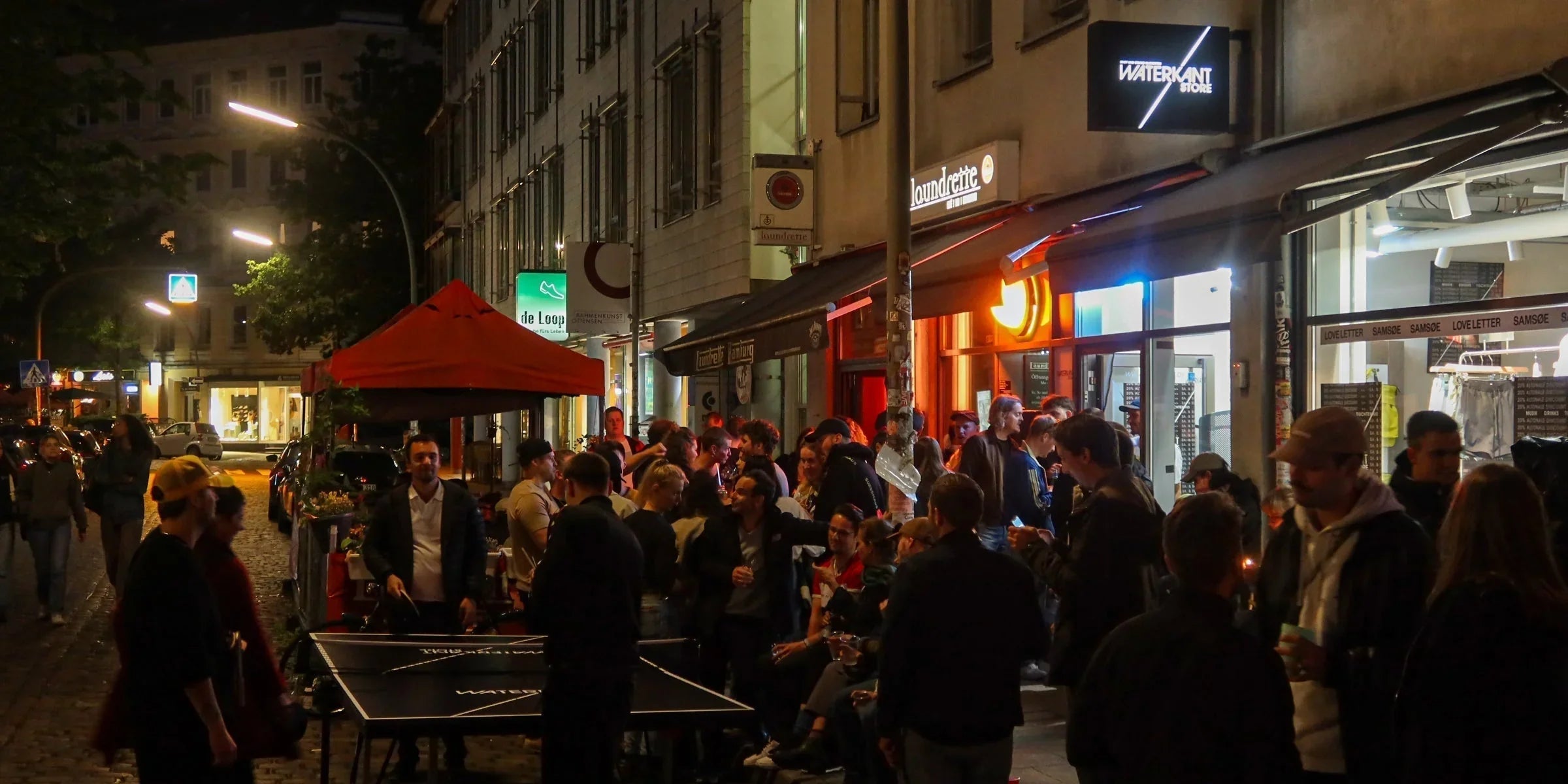 Menschenmenge vor dem WATERKANT Store während der Altonale in Hamburg bei Nacht.